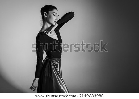 A young elegant, emotional ballet dancer, dressed in professional attire, demonstrates her dancing skills, hand movements. The beauty of classical ballet. Low key, Chernobyl photo