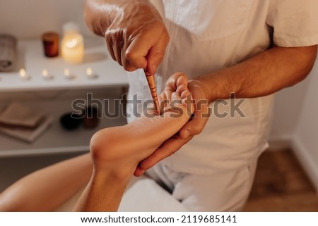 Acupuncture foot massage with thai stick. Acupressure, reflexology in alternative medicine. Oriental therapy through energy points on body. Wellness and SPA in Thailand. Royalty-Free Stock Photo #2119685141