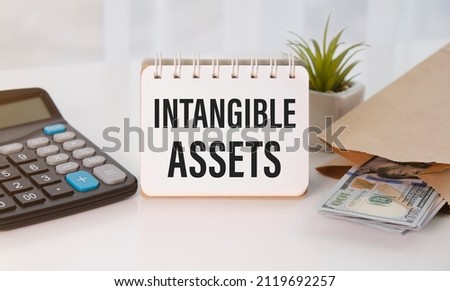 Intangible Asset text on an open notepad near the calculator and money dollars. Royalty-Free Stock Photo #2119692257
