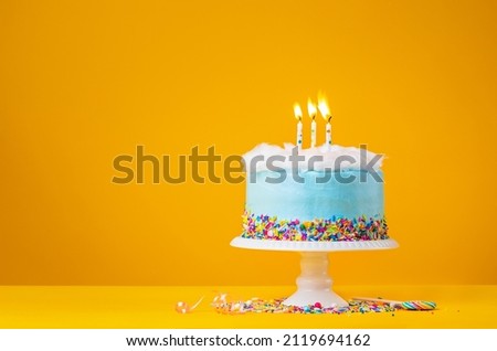 Blue Birthday Cake with three Candles over a yellow Background