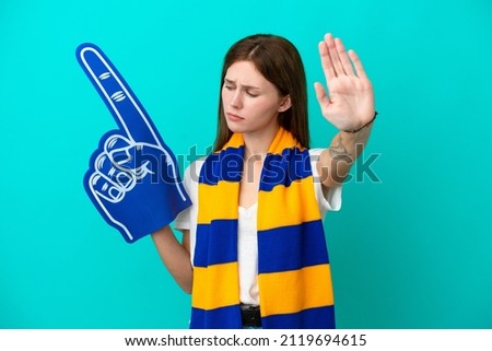 Young sports fan woman isolated on blue background making stop gesture and disappointed