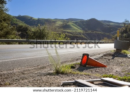 Knocked over traffic cone and road sign on asphalt mountain highway