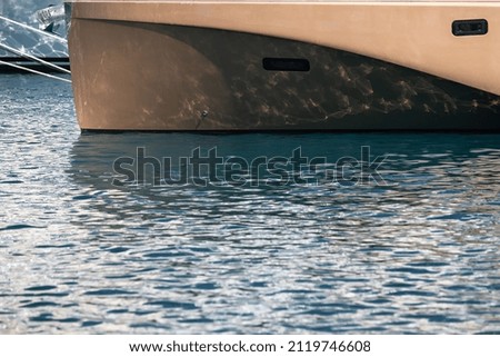 The mesmerizing reflection of the water on the glossy side of a huge yacht anchored, chrome details