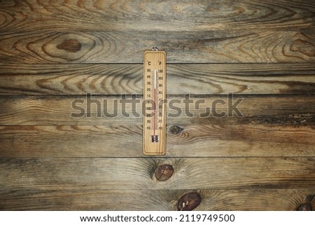 A studio photo of an outdoor wooden thermometer