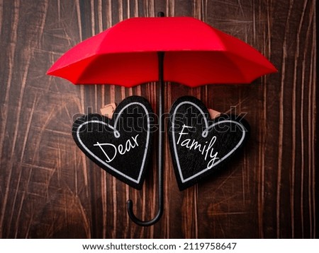 Top view umbrella and wooden love board with text Dear Family on a wooden background.