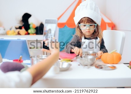 
Mother Taking a Picture of her Daughter Wearing a Chef Costume. Mom capturing memories while playing along her little child at home

