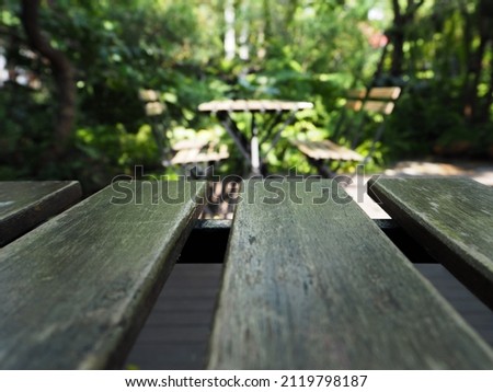 Empty wood table top and blurred view from green tree garden background	

