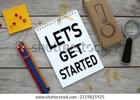 Let's Get Started. open notepad on wooden table with pencils
