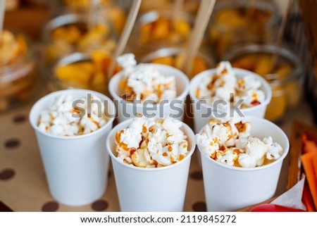 Cups of popcorn with caramel. Crispy sweetness. A bucket of popcorn for a trip to the movies. Five servings of delicious popcorn with caramel. High quality photo