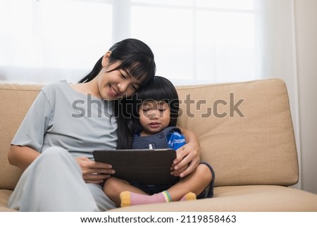Happy asian family mother and  son using tablet for education. Little boy watching funny social media.  Mom with kid using tablet video call to father.