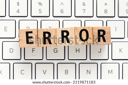 The word ERROR made of wooden letters arranged on a white computer keyboard.