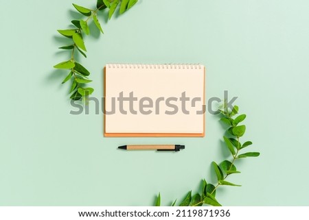 Creative flat lay photo of workspace desk. Top view office desk with open mockup blank notebooks and pencil and plant on pastel green color background. Top view with mock up copy space photography.