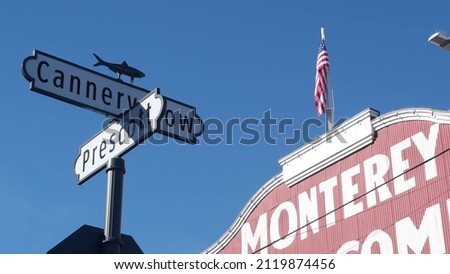 Red building, Cannery Row road sign, Monterey city, California tourist landmark, USA. Fisherman wharf, retro industrial street with canning companies, sardines factory. Travel destination sightseeing. Royalty-Free Stock Photo #2119874456