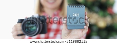 Young woman photographer holding calendar for 2022. In-demand profession of a photographer concept