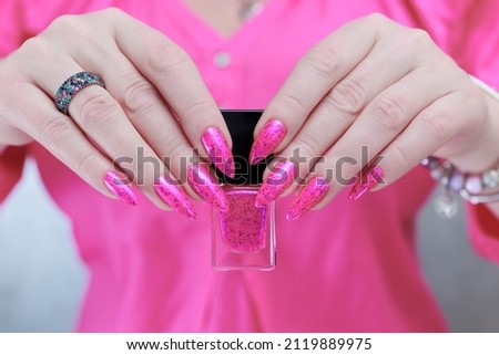 beautiful female hands with long nails and bright neon pink nail polish
