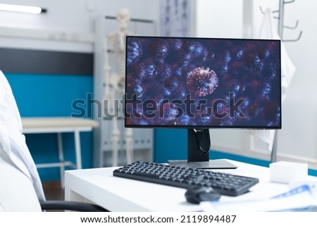 Empty hospital office room equipped with professional medical intruments ready for covoid19 examination. Computer with cornavirus illustration on screen during global pandemic. Virus image Royalty-Free Stock Photo #2119894487