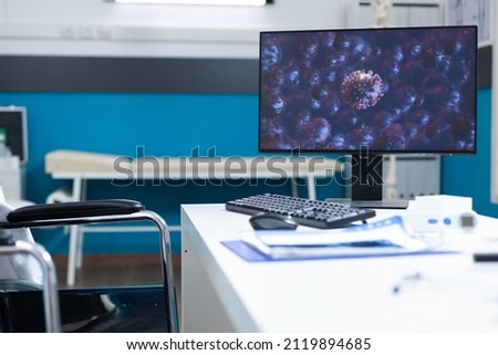 Empty bright medical office with computer standing on desk table having cornavirus illustration on screen during covid19 global pandemic. Hospital room equipped with professional tools. Virus image Royalty-Free Stock Photo #2119894685
