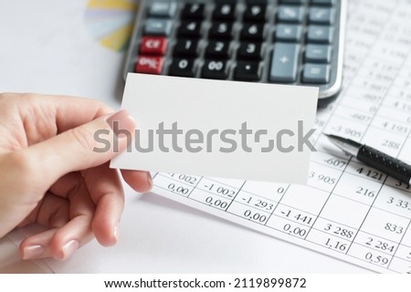 hand with an empty business card on the background of an office desk, a business concept