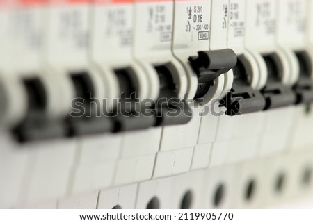 One current circuit breaker turned on among many disconnected ones. Close-up. Royalty-Free Stock Photo #2119905770