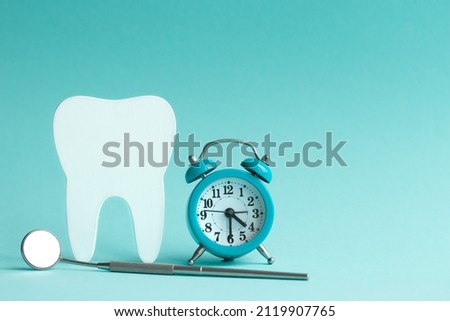 White human tooth figurine on a blue background with a clock and a dental mirror with space for text Royalty-Free Stock Photo #2119907765