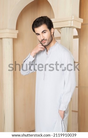 A  man is posing for the fashion shoot in indoor studio