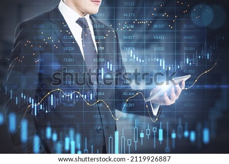 Close up of businessman hand holding tablet with abstract glowing big data forex candlestick chart on blurry office interior background. Trade, technology, investment and analysis concept. 