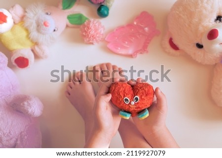 Child holding handmade soft heart, cute craft for Valentines day or birthday. DIY