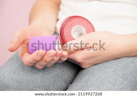 The beautician holds kinesio tapes in her hands, cropped view. Anti-aging procedures
