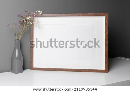 Landscape wooden frame mockup for artwork, photo and print presentation with dry flowers interior decorations over grey wall.