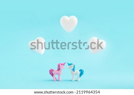 Pink and blue unicorn in love with white hearts on a pastel blue background. Minimal concept of Valentine's Day, love, togetherness.