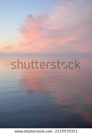 Baltic sea at sunset. Clear sky, blue and pink glowing clouds, soft golden sunlight. Water surface texture. Picturesque dreamlike seascape, cloudscape, nature. Panoramic view Royalty-Free Stock Photo #2119970351