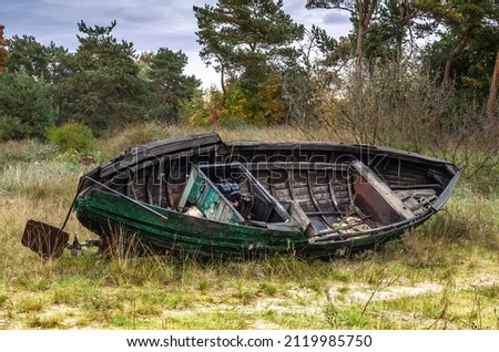 Old broken and abandoned wooden fishing boat on a forest beach of the Baltic Sea