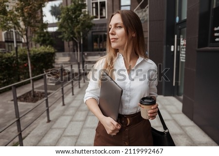 Close up portrait business woman holding coffee and laptop of the building background 