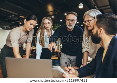 Focused businesspeople having a discussion while collaborating on a new project in an office. Group of diverse businesspeople using a laptop while working together in a modern workspace. Royalty-Free Stock Photo #2119997411