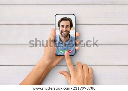 Virtual Date Concept. Point of view of unrecognizable female using smartphone to talk with young man online. Woman calling her boyfriend, above top overhead view, isolated on wooden background