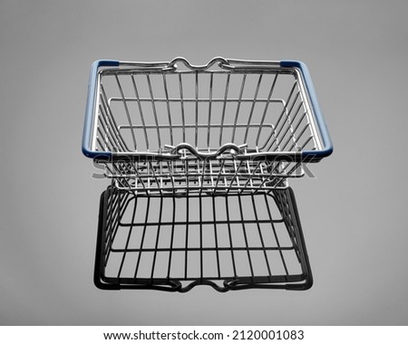 Empty shopping basket for supermarket products on a gray glossy background. Retail store equipment. The concept of marketing and buying consumer goods