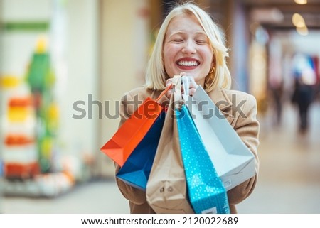 Excited woman having fun shopping and holding bags while looking at the camera smiling. Beautiful woman holding shopping bags and smiling. Young beautiful girl is shopping in the Mall 
