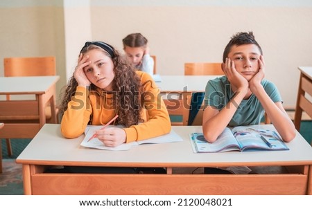 Bored students sitting at school desk during the class.	
