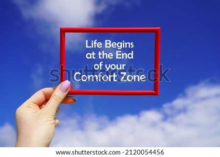 Life begins at the end of your Comfort Zone. Red frame in a female hand against the blue sky. Go beyond thinking. Motivational concept