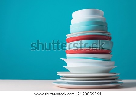 Pile of colorful clean dishes on light blue background
