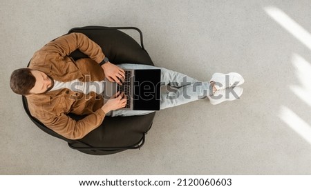 Male Freelancer Using Laptop Computer With Blank Screen Sitting In Chair At Home. Technology And Gadgets, Freelance Career And Lifestyle Concept. Top View Shot, Panorama, Mockup Royalty-Free Stock Photo #2120060603