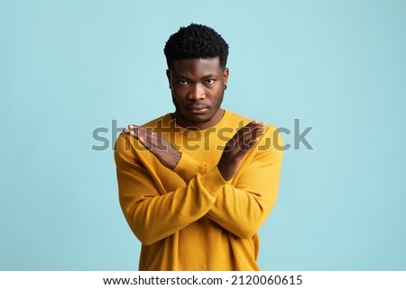 Serious african american millennial guy in casual saying no, looking at camera and showing hands crossed over chest, blue studio background, copy space. Human gestures concept Royalty-Free Stock Photo #2120060615
