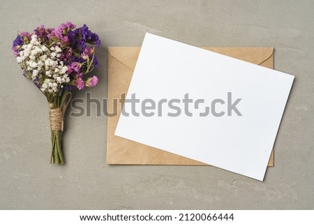 Flowers, blank paper and envelope on a table top view Royalty-Free Stock Photo #2120066444