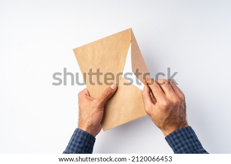 Top view photo of male hands   hold (open) an envelope above white background