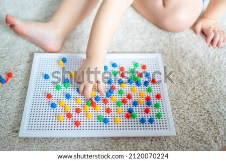 Pretty little girl playing with mushroom nail mosaic at home. Hobby and leisure time. High quality photo