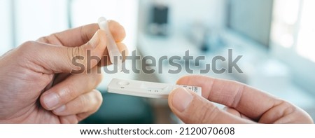 a young man places his own sample into the covid-19 antigen diagnostic test device in the office, in a panoramic format to use as web banner or header Royalty-Free Stock Photo #2120070608