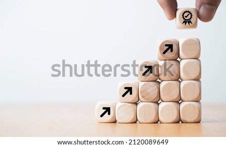 Hand putting virtual quality assurance and arrow which print screen on wooden cube for quality enhancement of  guarantee product and ISO service concept. Royalty-Free Stock Photo #2120089649