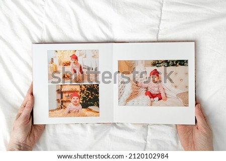hands with book with photos of little child in photo studio on a white background.Photobook is gift. professional photographer and designer.printing of photos and journals in photo laboratory
