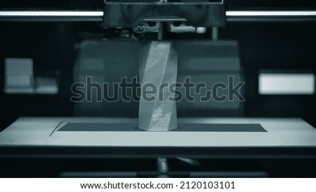 3D printer works and creates an object from the hot molten plastic close-up. Automatic three dimensional 3d printer performs plastic red colors modeling in laboratory. Royalty-Free Stock Photo #2120103101