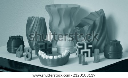 Models printed by 3d printer. Objects printed on 3d printer on table. Automatic three dimensional printer performs plastic modeling in laboratory. Progressive modern additive technology Royalty-Free Stock Photo #2120103119